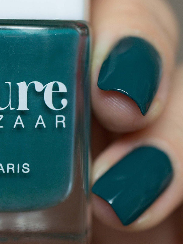 Naglar målade med Kure Bazaar Green Love bredvid flaskan