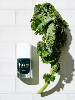 Kure Bazaar nagellack Kale bredvid ett grönkålsblad