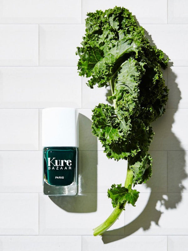 Kure Bazaar nagellack Kale bredvid ett grönkålsblad
