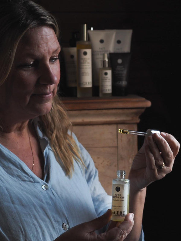 Kvinna droppar c/o Gerd Pure Jojoba Oil i handen