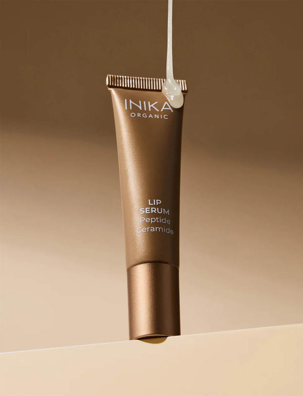 INIKA Tinted Lip Serum i guldfärgad tub mot beige bakgrund
