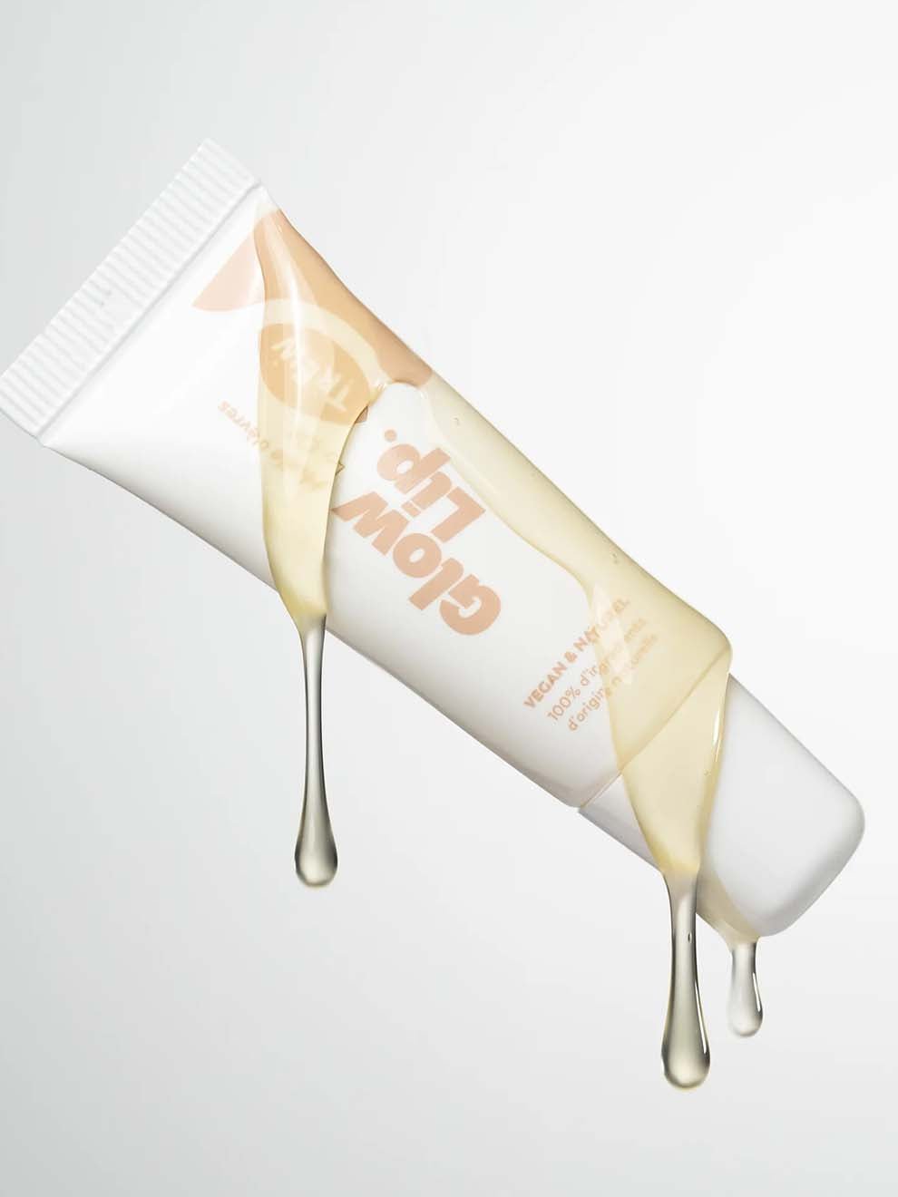Trew Glow Lip läppolja i tub bredvid genomskinliga klickar